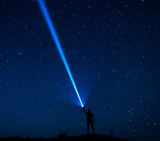 Person directing light into the night sky, representing ML arteka's path from data to AI.